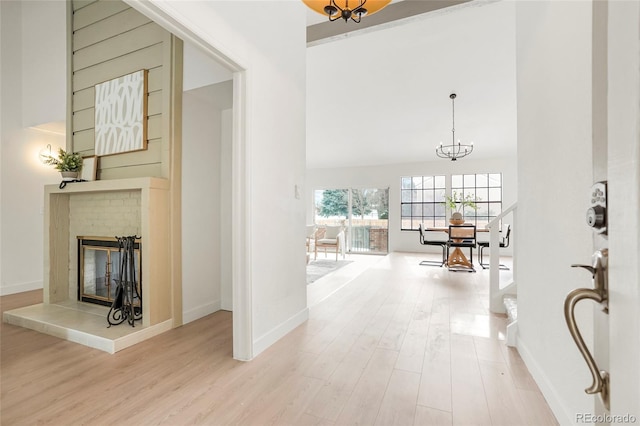 hall featuring a towering ceiling, a notable chandelier, and light hardwood / wood-style floors