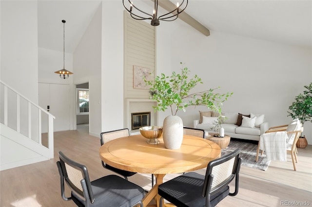 dining room featuring light wood-type flooring, beam ceiling, high vaulted ceiling, and a notable chandelier