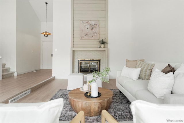 living room featuring hardwood / wood-style floors, a towering ceiling, and a brick fireplace