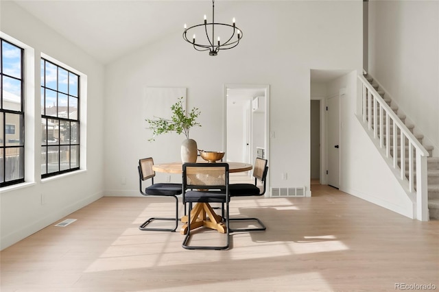 dining area featuring a notable chandelier, high vaulted ceiling, and light hardwood / wood-style flooring