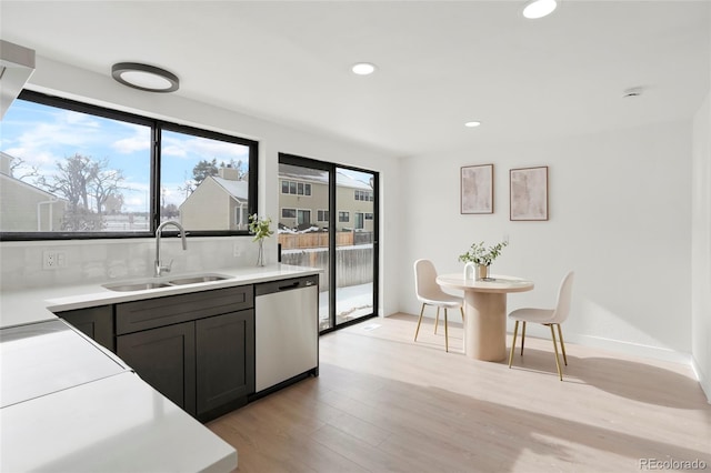 kitchen featuring a wealth of natural light, dishwasher, sink, and light wood-type flooring