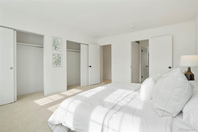 bedroom with light carpet and two closets