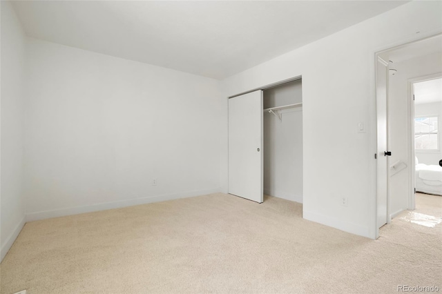 unfurnished bedroom featuring light colored carpet and a closet