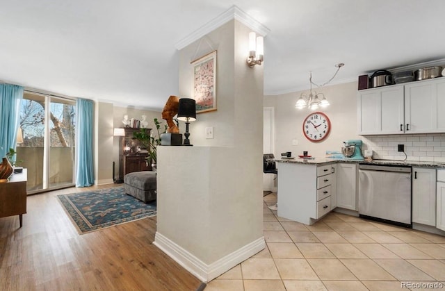 kitchen with pendant lighting, tasteful backsplash, dishwasher, white cabinets, and kitchen peninsula