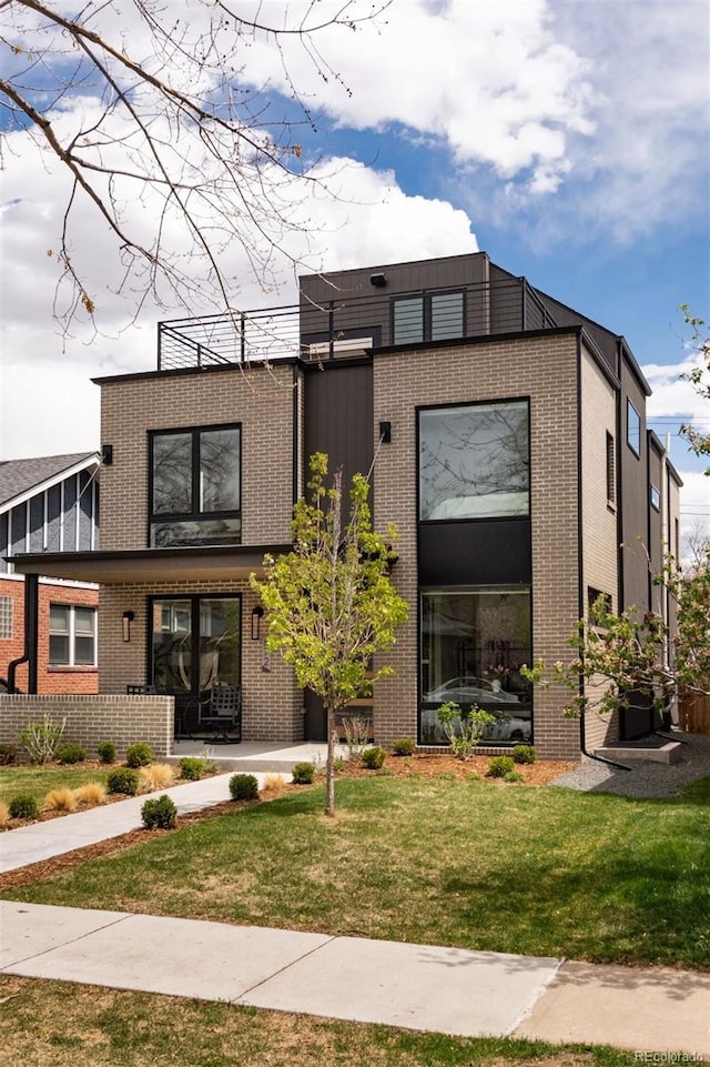 contemporary house with brick siding and a front yard