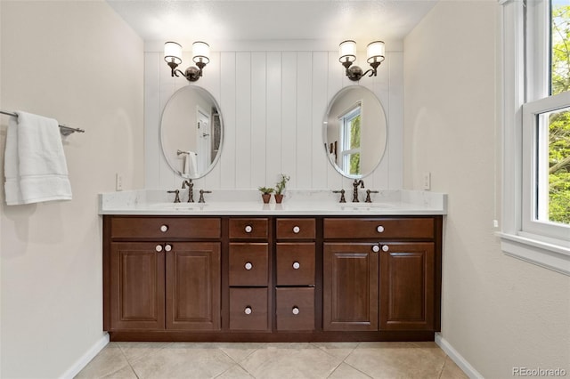 bathroom featuring baseboards, tile patterned floors, and double vanity