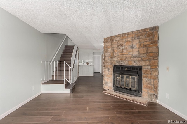 unfurnished living room featuring stairway, wood tiled floor, a stone fireplace, and baseboards