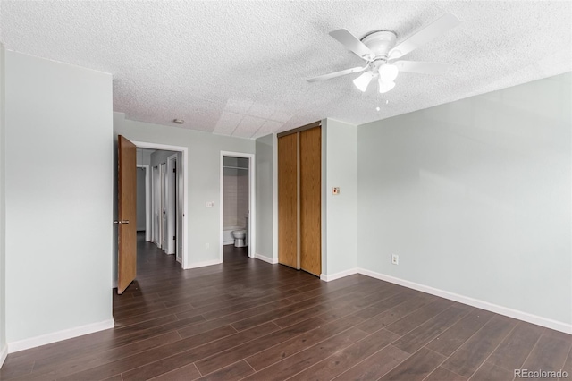 unfurnished room featuring ceiling fan, baseboards, dark wood finished floors, and a textured ceiling