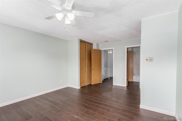 spare room featuring dark wood-style flooring, ceiling fan, a textured ceiling, and baseboards