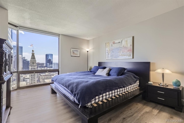 bedroom featuring hardwood / wood-style flooring, a wall of windows, and a textured ceiling