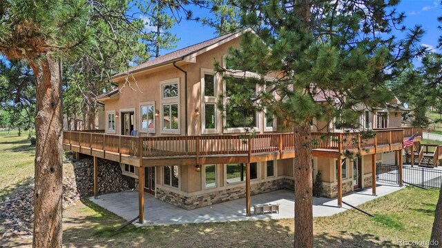 rear view of house featuring a wooden deck and a patio