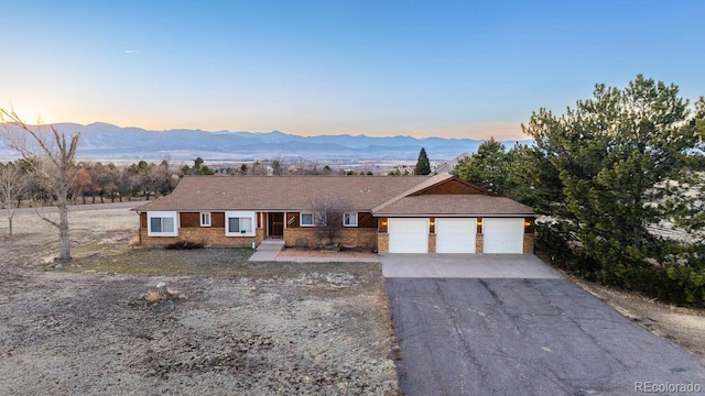 ranch-style house featuring aphalt driveway, a garage, and a mountain view