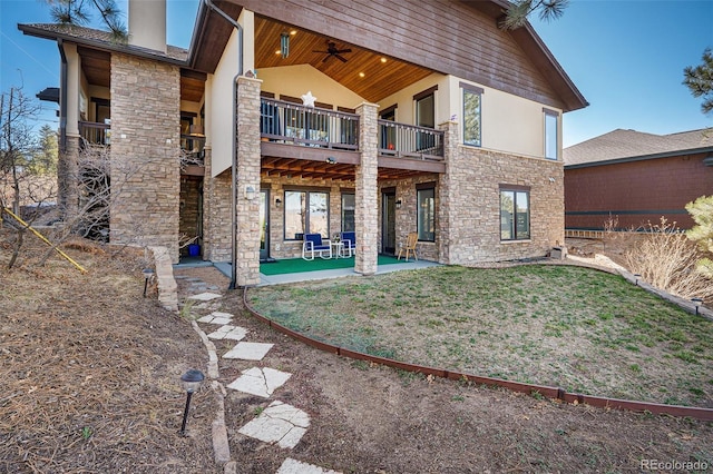 rear view of house with a ceiling fan, a patio, stucco siding, and stone siding