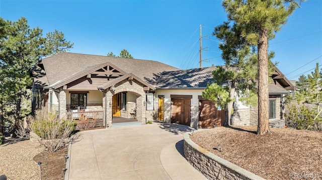 craftsman house with a porch, stone siding, a garage, concrete driveway, and roof with shingles