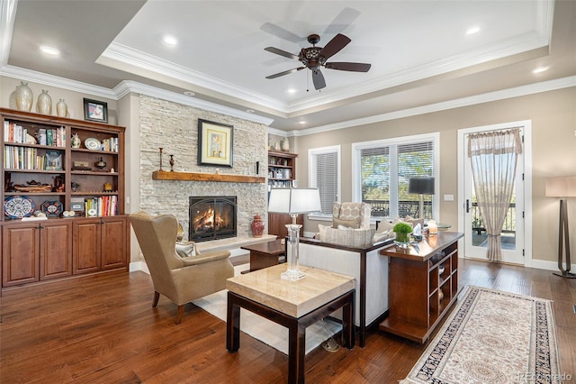 living area featuring a ceiling fan, a raised ceiling, a fireplace, and dark wood finished floors