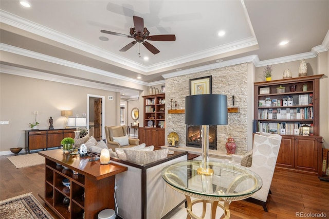 living area with a fireplace, ceiling fan, ornamental molding, and wood finished floors