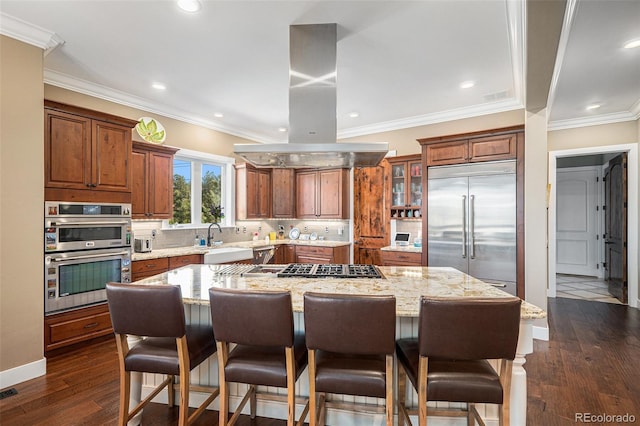 kitchen featuring island range hood, a kitchen island, brown cabinets, and appliances with stainless steel finishes