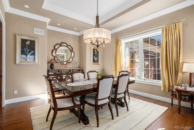 dining area featuring visible vents, a tray ceiling, an inviting chandelier, and hardwood / wood-style floors