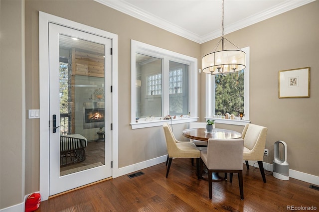 dining area with visible vents, an inviting chandelier, ornamental molding, a wealth of natural light, and wood finished floors