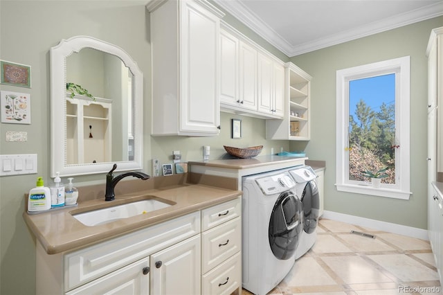 clothes washing area featuring baseboards, ornamental molding, washing machine and dryer, cabinet space, and a sink