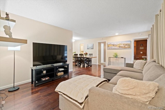 living room with a textured ceiling, baseboards, and dark wood-type flooring