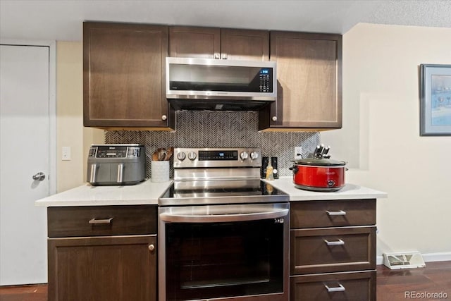 2306 S Troy St Unit A, Aurora, CO 80014 - kitchen featuring dark wood-style floors, dark brown cabinets, backsplash, light countertops, and appliances with stainless steel finishes