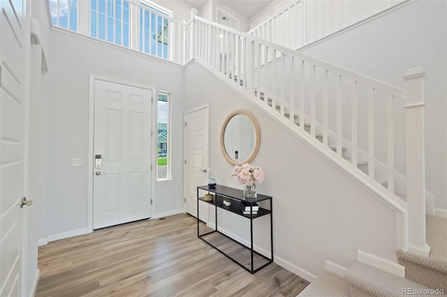 entrance foyer featuring stairway, a high ceiling, wood finished floors, and baseboards