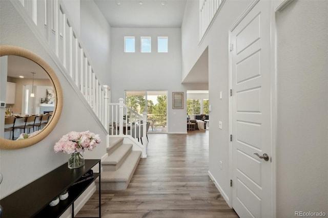 entryway featuring stairway, a high ceiling, baseboards, and wood finished floors