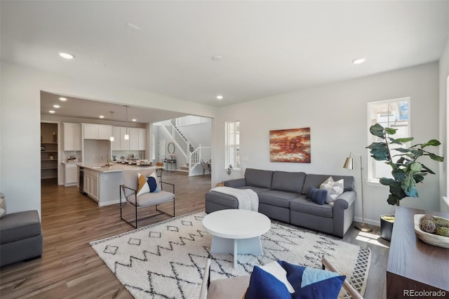 living room with recessed lighting, baseboards, light wood-style floors, and stairs