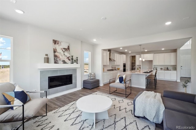 living room featuring recessed lighting, a tile fireplace, baseboards, and wood finished floors