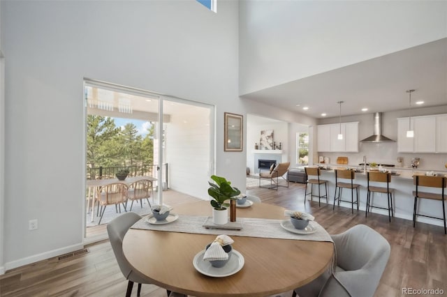 dining room with visible vents, baseboards, recessed lighting, wood finished floors, and a glass covered fireplace