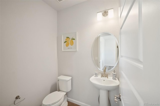 bathroom with toilet, baseboards, and a sink