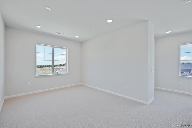 empty room featuring light carpet, recessed lighting, and baseboards