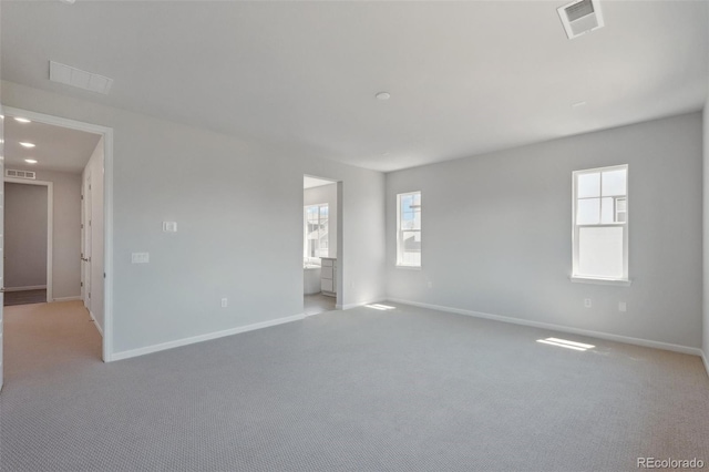 unfurnished room with light carpet, visible vents, and baseboards