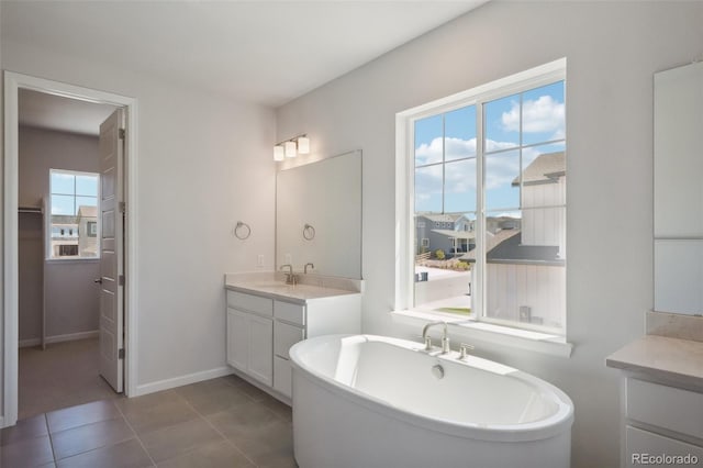 full bathroom with tile patterned floors, a freestanding tub, baseboards, and vanity