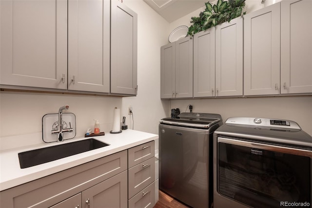 clothes washing area with cabinets, washer and clothes dryer, and sink