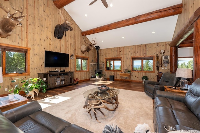 living room with beam ceiling, a wood stove, and plenty of natural light