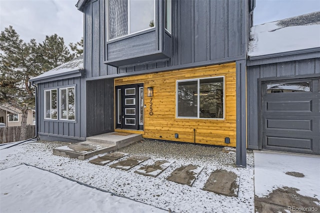 snow covered property entrance featuring a garage