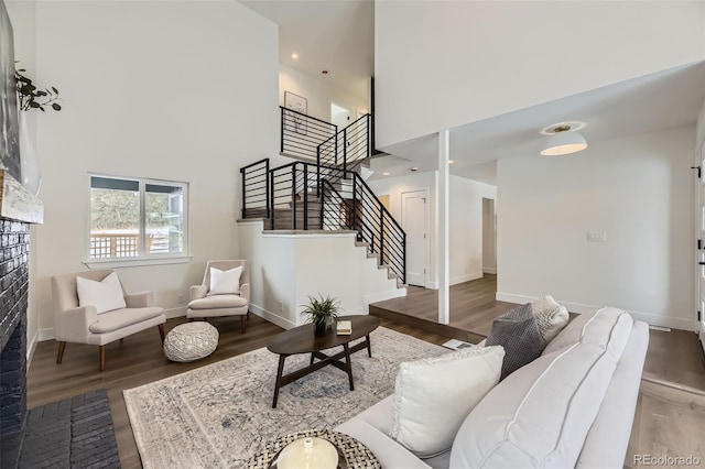 living room with a towering ceiling and dark wood-type flooring