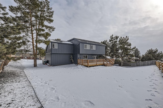 snow covered back of property with a wooden deck