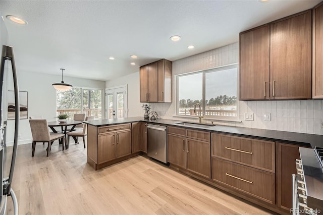 kitchen featuring pendant lighting, sink, stainless steel dishwasher, light hardwood / wood-style floors, and kitchen peninsula