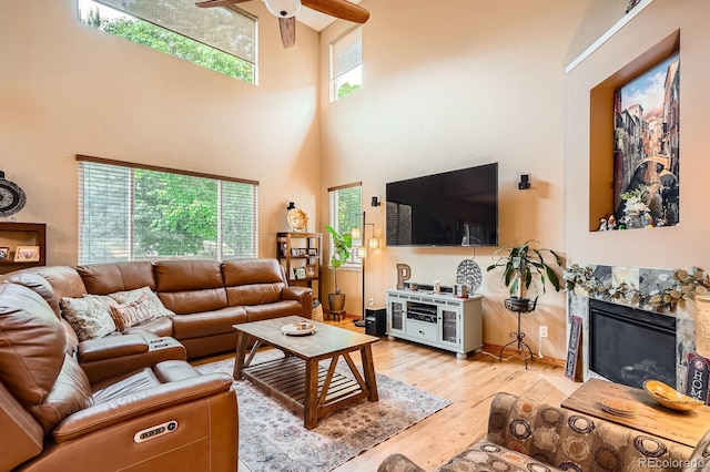 15056 Fillmore Way, Thornton, CO 80602 - living room featuring a high ceiling, ceiling fan, light wood-type flooring, and a tile fireplace