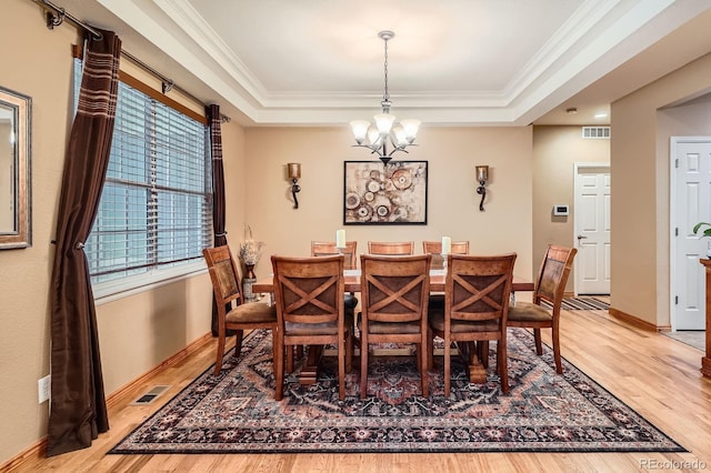 15056 Fillmore Way, Thornton, CO 80602 - dining area with light wood-type flooring, a chandelier, a raised ceiling, and ornamental molding