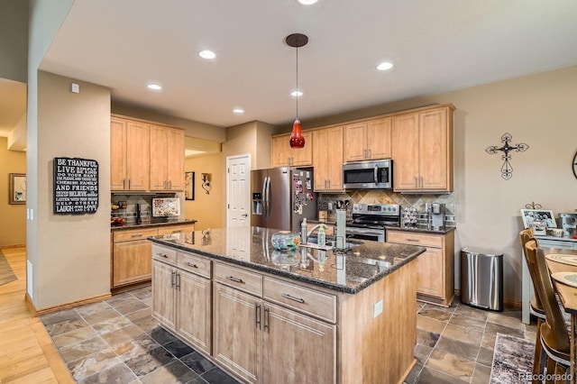 15056 Fillmore Way, Thornton, CO 80602 - kitchen with stainless steel appliances, an island with sink, tasteful backsplash, light brown cabinetry, and stone tile floors