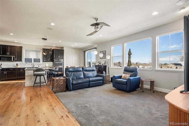 living room featuring light hardwood / wood-style floors, ceiling fan, and sink