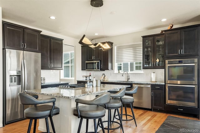 kitchen with appliances with stainless steel finishes, a center island, hanging light fixtures, and a breakfast bar area