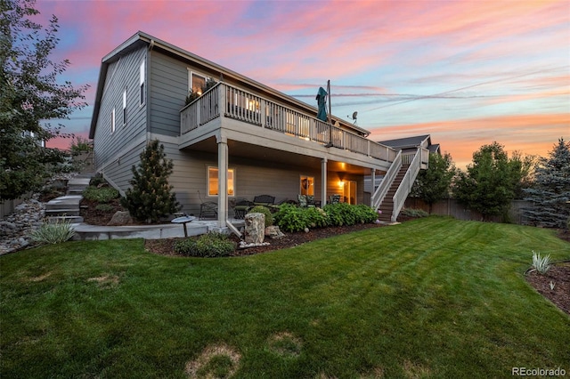 back house at dusk featuring a yard and a deck