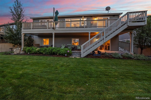 back house at dusk featuring a deck and a yard