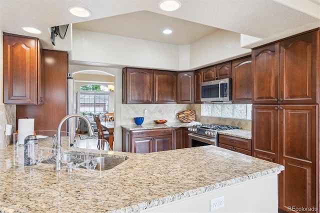 3305 White Oak Ln, Highlands Ranch, CO 80129 - kitchen featuring stainless steel appliances, light stone counters, arched walkways, tasteful backsplash, and recessed lighting