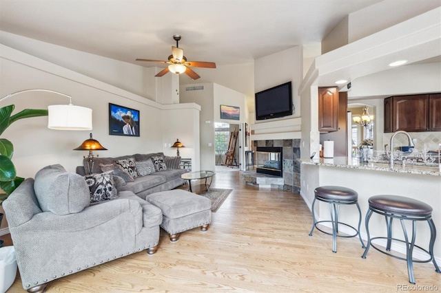 3305 White Oak Ln, Highlands Ranch, CO 80129 - living area featuring vaulted ceiling, light wood-type flooring, a ceiling fan, a fireplace, and a chandelier